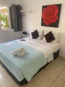 um quarto com uma cama grande e uma pintura de rosa vermelha na parede em Hotel Pousada Iracemar - Guarujá no Guarujá