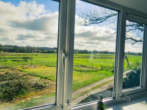 a window with a view of a field at The Plough Inn Farmhouse - Private Holiday House in Lenwade