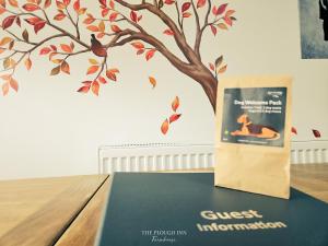 a book sitting on a table with a tree on the wall at The Plough Inn Farmhouse - Private Holiday House in Lenwade +43 photos