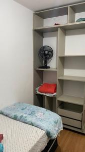 a room with a bed and a shelf with a fan at Park marilandia 507 in Juiz de Fora