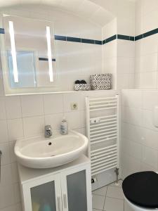 a white bathroom with a sink and a mirror at Apartment Arenablick in Leipzig