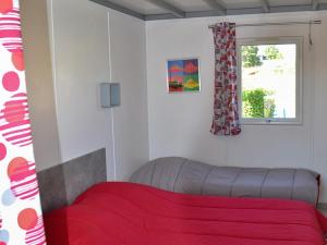 - une chambre avec un lit rouge et une fenêtre dans l'établissement Les Pommiers de Mont Saint Michel, à Beauvoir
