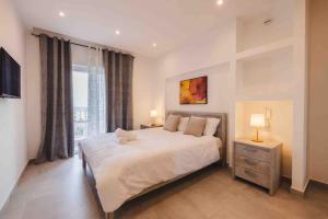 a bedroom with a large white bed and a window at Luxurious in Is-Swieqi