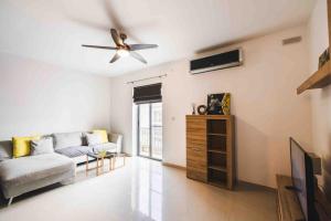 a living room with a couch and a ceiling fan at Blossom Bliss apartment in Msida