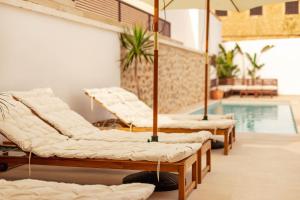 una fila di materassi seduti accanto alla piscina di Ōrigins Hotel Boutique - Adults Only ad Artá
