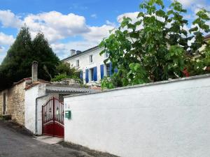 una casa blanca con una puerta roja y una valla blanca en Maison de 3 chambres avec jardin clos et wifi a Fleurac, en Fleurac