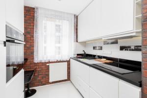 una cocina con armarios blancos y una pared de ladrillo en Osiedle Avia Modern Apartment, en Cracovia