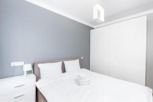 a white bedroom with two beds and a dresser at Osiedle Avia Modern Apartment in Krakow