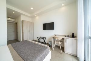 a bedroom with a bed and a desk and a television at Poseidon Rooms in Cagliari