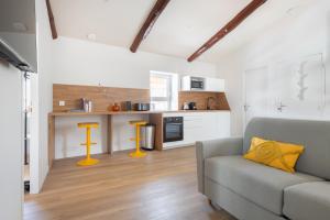 a living room with a couch and a kitchen at Pin * Spacieux * Linge hôtelier * Fibre * Confort in La Destrousse
