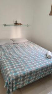 a bed with a blue and white comforter in a room at Apartamento Farolandia in Aracaju