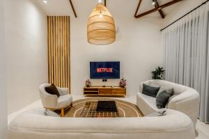 a living room with two chairs and a tv at Berapi Villa by EVDEkimi - Elegant 3BR Ubud Home with Pool & Kitchen near Central Ubud in Ubud