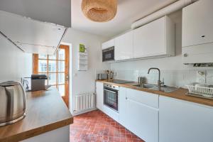 a kitchen with white cabinets and a sink at Villa des Malons - Maison à 100m de la plage in Saint-Aubin-sur-Mer