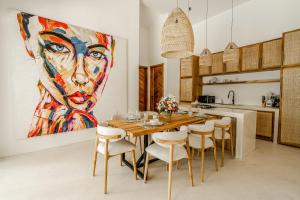 a dining room with a large painting of a woman at Berapi Villa by EVDEkimi - Elegant 3BR Ubud Home with Pool & Kitchen near Central Ubud in Ubud
