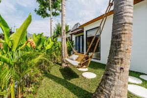a dog sitting in a swing in front of a house at Berapi Villa by EVDEkimi - Elegant 3BR Ubud Home with Pool & Kitchen near Central Ubud in Ubud