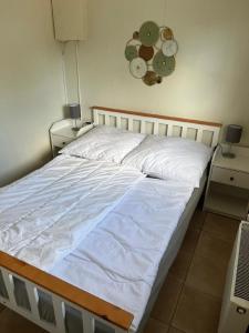un letto con lenzuola bianche e un orologio a muro di Charmantes Ferienhaus in Wervershoof mit Terrasse und Grill a Wervershoof Altre 14 foto