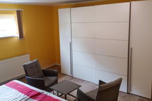 a bedroom with a white closet with chairs and a table at Ferienwohnung Balmer Wiesen in Balm