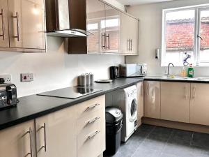 a kitchen with white cabinets and a washer and dryer at Liverpool City Centre - Spacious Duplex - 6 Bedrooms - Sleeps 14 People in Liverpool