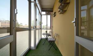 einen Balkon mit 2 Stühlen, einem Tisch und Fenstern in der Unterkunft Triumvirato Rooms in Bologna