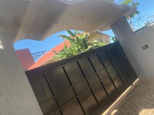 einen Blick durch einen Bogen eines Gebäudes mit einem Zaun in der Unterkunft HA Luxury Air B&B in Kampala