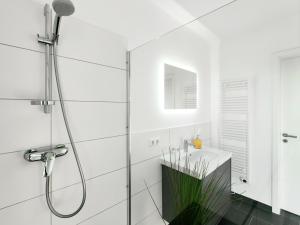 a white bathroom with a shower and a sink at Penthouse mit Whirlpool bei Hannover in Burgwedel