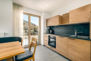 cocina con armarios de madera, mesa y ventana en Untermoarhof Albeins, en Bresanona