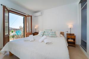 ein Schlafzimmer mit einem weißen Bett und einem großen Fenster in der Unterkunft Townhouse Lleo 72 By homevillas360 in Pollença