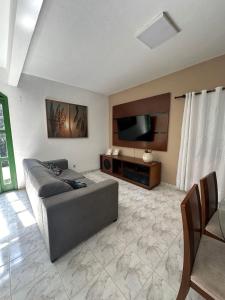 een woonkamer met een bank en een flatscreen-tv bij Sítio com piscina e churrasqueira in Guapimirim