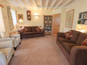 a living room with two couches and a book shelf at Hollens Cottage in Grasmere