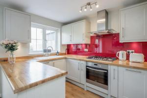 a kitchen with red walls and white cabinets at Detached Luxury Stylish House - Staycation - Hot Tub in Warfield