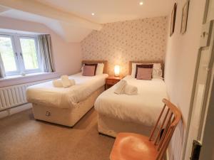 a bedroom with two beds and a chair in it at Hollens Cottage in Grasmere