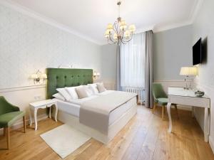 a bedroom with a white bed and a chandelier at Hotel Lomnica in Vysoke Tatry - Tatranska Lomnica.