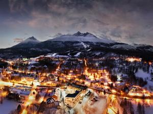 une ville dans la neige la nuit avec des montagnes dans l'établissement Hotel Lomnica, à Tatranská Lomnica