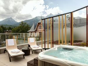 a jacuzzi tub on a balcony with mountains at Hotel Lomnica in Tatranská Lomnica