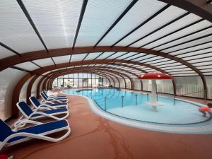 a large swimming pool with lounge chairs in a building at Mobile-home Camping 4 etoiles bord de mer in Ouistreham