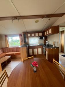 a kitchen and living room with a table with a flower on it at Mobile-home Camping 4 etoiles bord de mer in Ouistreham