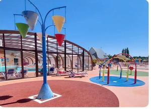 a park with a playground with slides and swings at Mobile-home Camping 4 etoiles bord de mer in Ouistreham