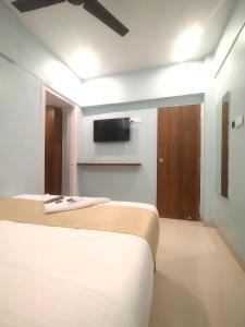 a bedroom with two beds and a tv on the wall at Everest Stays Rooms and Dormitory in Mumbai