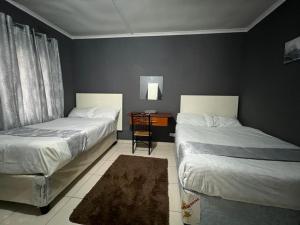 1 dormitorio con 2 camas y mesa con silla en Golden bamboo en Masvingo
