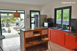 a kitchen with red cabinets and a view of a patio at Loc974 Les Cocotiers in Saint-Leu