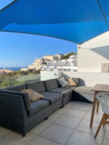 a couch sitting on a patio under a blue umbrella at 414 Casa Colina Mar in Salema