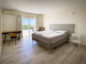 a bedroom with a bed and a desk and a window at 414 Casa Colina Mar in Salema