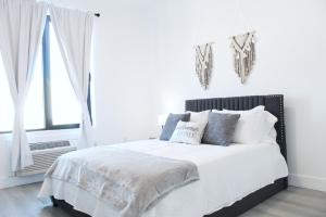 une chambre blanche avec un grand lit avec des oreillers dans l'établissement Cozy Stylish Apartment near Newark, NJ Airport, à Elizabeth