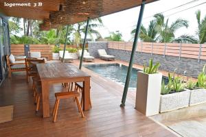 a patio with a table and chairs and a swimming pool at Loc974 Les Cocotiers in Saint-Leu