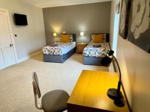 a room with two beds and a desk and a table at 3 Castle Hume Court Holiday House in Enniskillen