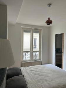 a white bedroom with a bed and a window at No Matter Stay - Chic and classy - Arc de Triomphe in Paris