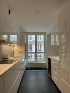 a kitchen with white cabinets and a large window at No Matter Stay - Chic and classy - Arc de Triomphe in Paris