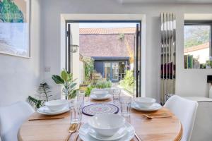 a dining room with a wooden table with plates and glasses at Stylish 2BD with Private Garden and Sauna in Oxford