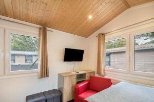 une chambre avec un lit, une télévision et une chaise rouge dans l'établissement Tiny House Lohmen Garder See, à Lohmen
