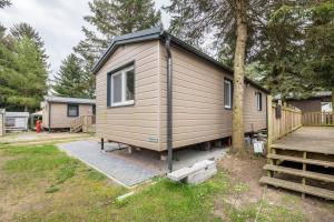 une petite maison assise à côté d'un arbre dans l'établissement Tiny House Lohmen Garder See, à Lohmen